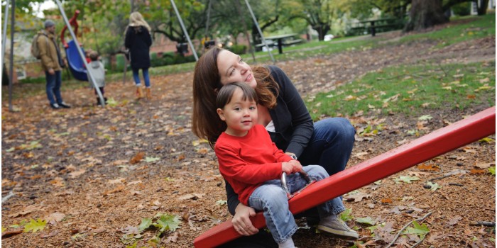 mom and son play on see saw at the park